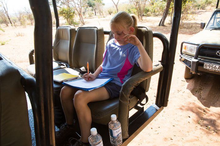 Kara doing her homework from the back seat of a safari jeep.