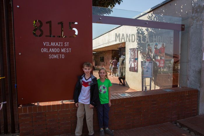 Tyler and Kara in front of a sign that reads "Mandela House."