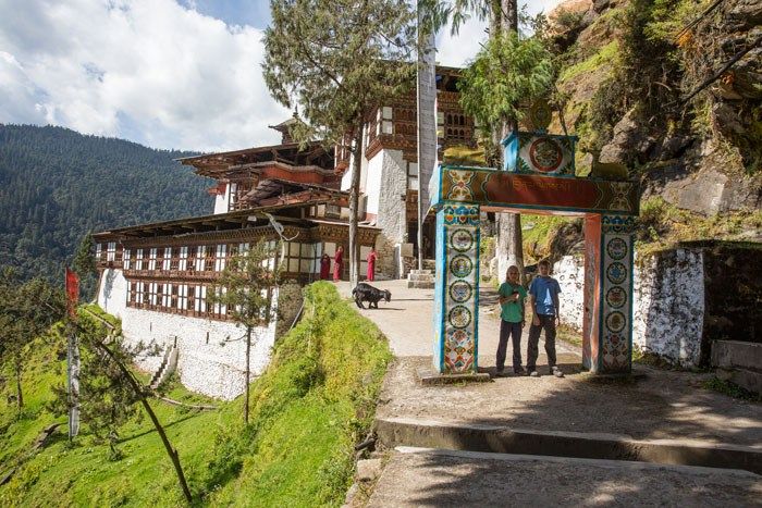 Two kids stand in the archway entrance to the Cheri Monastery in Bhutan.