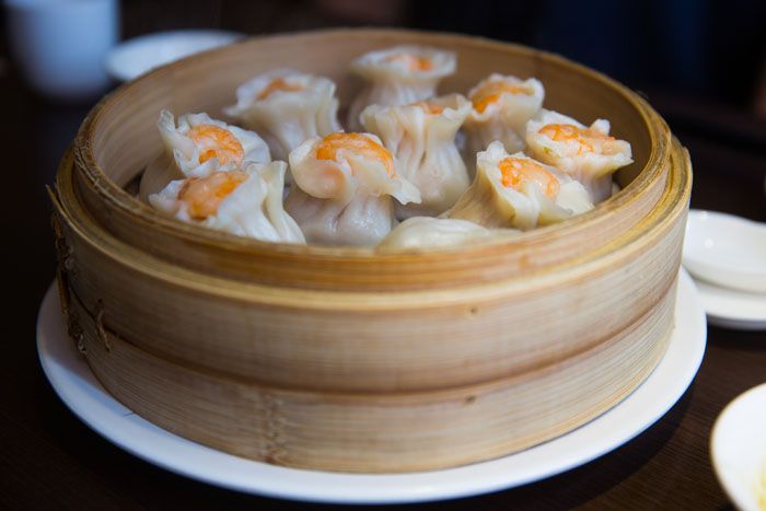 A bowl of steamed dumplings served in a round bamboo container.