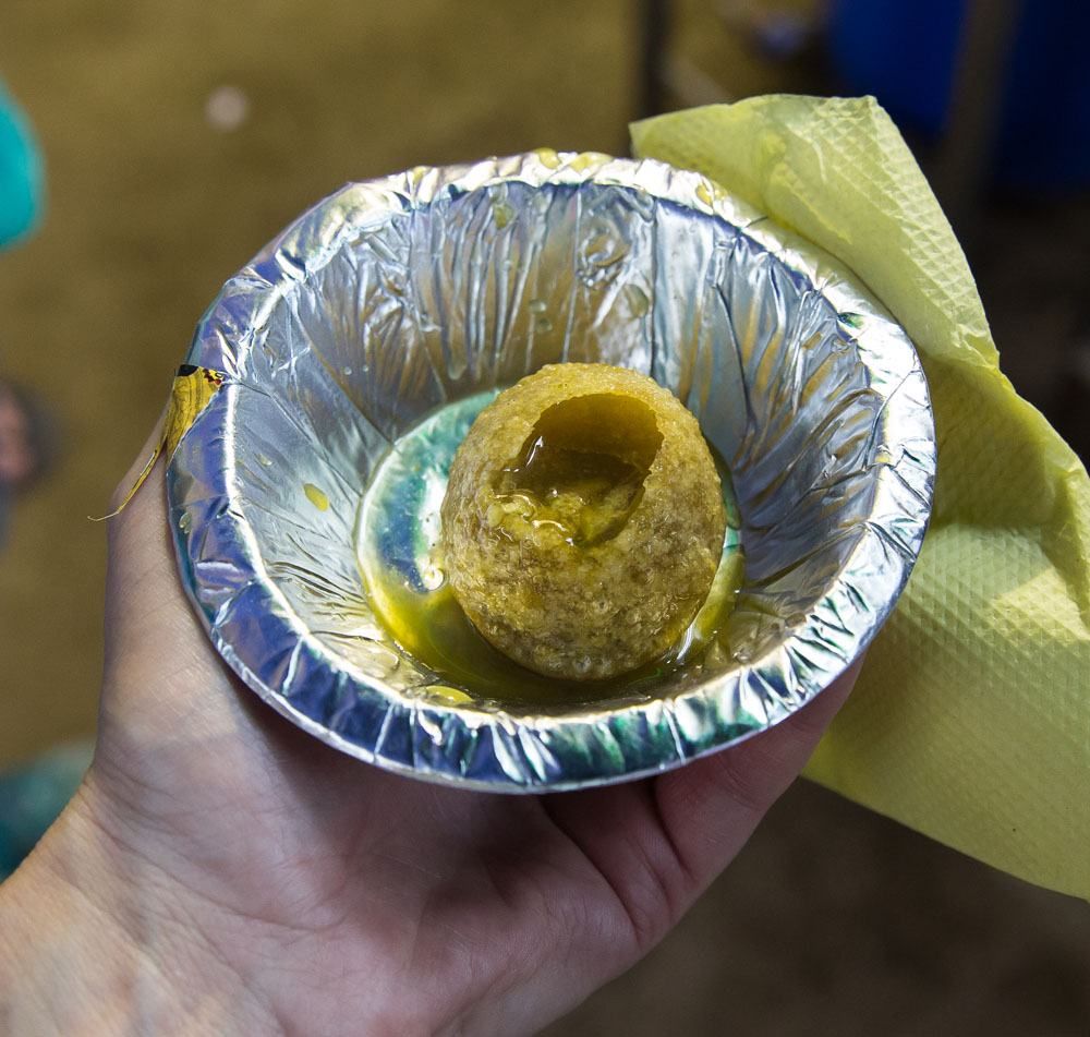 A hollow ball of crusty dough, punctured and filled with a green liquid and served in a tinfoil-lined bowl.