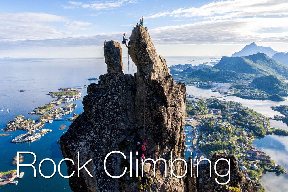 A group of climbers climbing a tall rock formation with the ocean in the background.