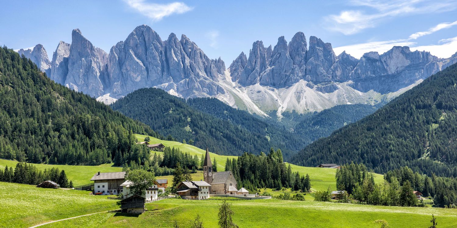 a village in a valley with mountains in the background with Dolomites in the background